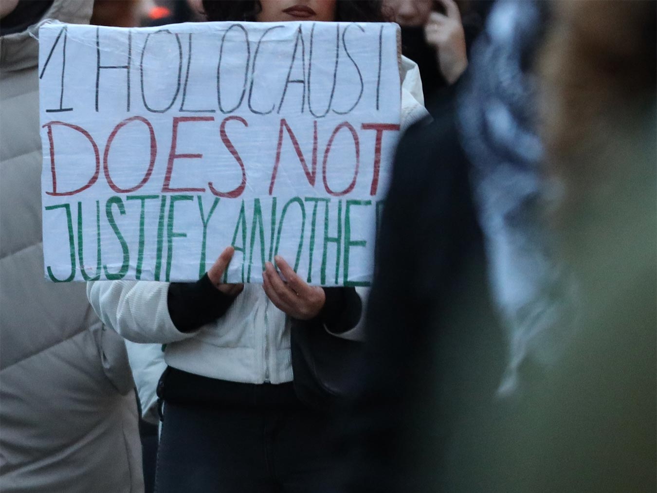 Person mit Schild »1 Holocaust does not justify another«